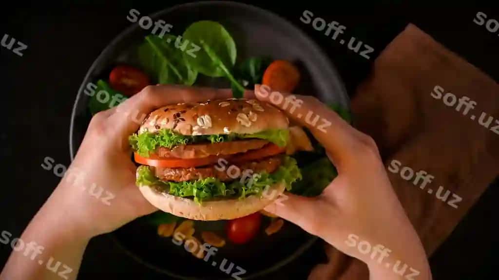 Yaqin suratda qo'llar mazali vegan burger, soya proteinli burger, yangi sabzavotlar bilan o'simlik asoslangan ovqatni tutib turibdi. | Closeup hands hold tasty vegan burger soy protein burger with fresh vegetables plant based food