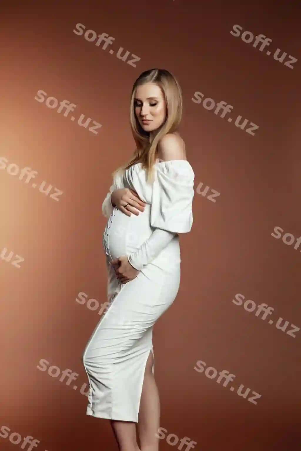 Yosh homillik qilayotgan ayol jigarrang fonda turibdi, foto studio da olingan rasm. | Young pregnant woman dress is standing brown background photo taken photo studio