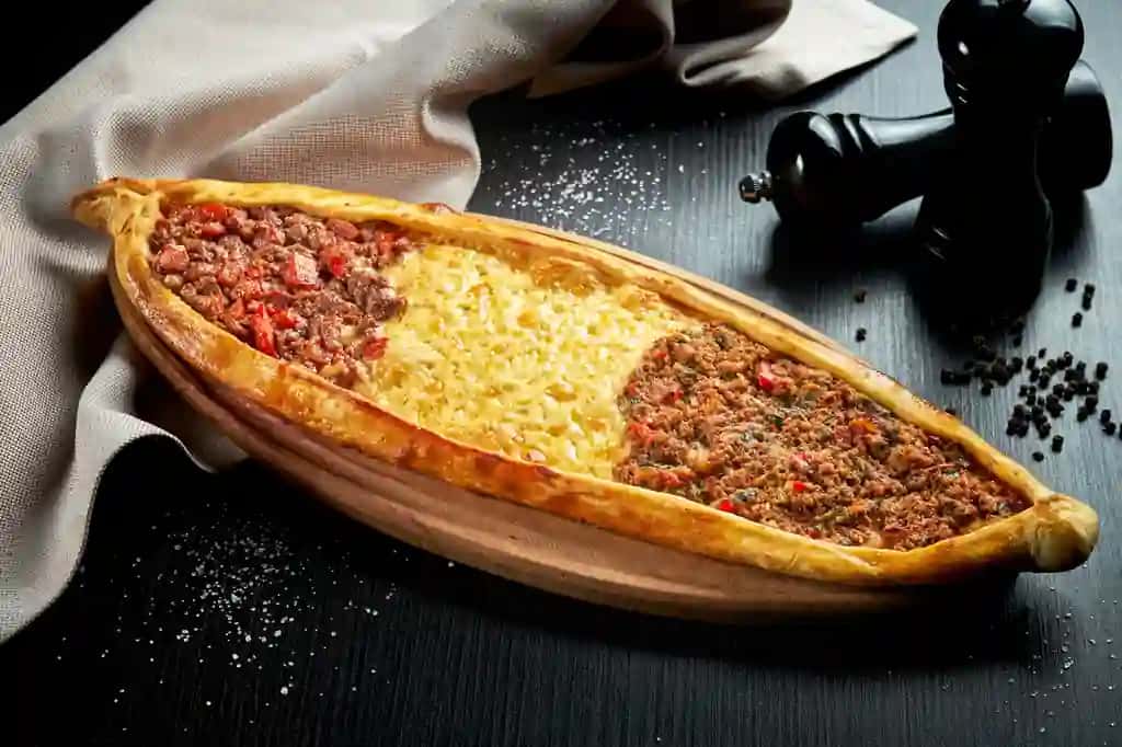 Uch xil nachinkali turkcha pide taomi qo'y go'shti mol go'shti cheddar pishloq qora stol yaqindan suratga olingan tanlangan fokus | Turkish pide dish with three different fillings lamb beef cheddar cheese black table close up selective focus