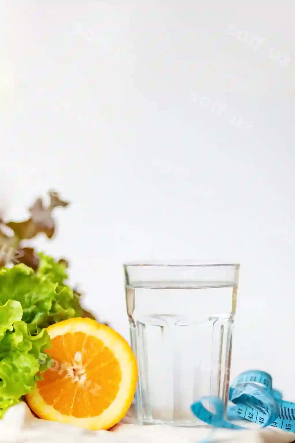 Salat varaqi apelsin piyolasi suv o'lchash ko'k qo'g'irchoq oq fonda matn uchun nusha joy bilan sog'lom turmish tarzi ichim suvi tushunchasi | Salade leaf orange cup water measuring blue tape white background with copy space text healthy lifestyle drinking water concept