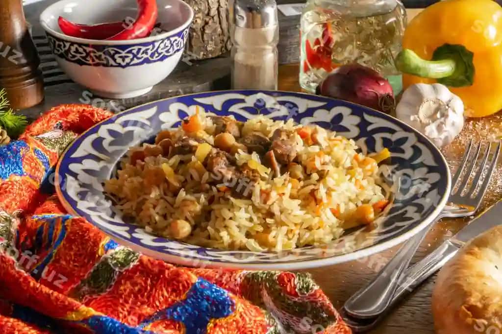 Palov qo'y bilan an'iy sharqiy issiq taom guruch, qo'y, sariq morkov' sarimsoqli, shirin chukha, no'xat, kumiroq, milliy o'zbek naqshli likop | Pilaf with lamb traditional oriental hot dish rice lamb yellow carrots with garlic raisins chickpeas turmeric plate with national uzbek ornament