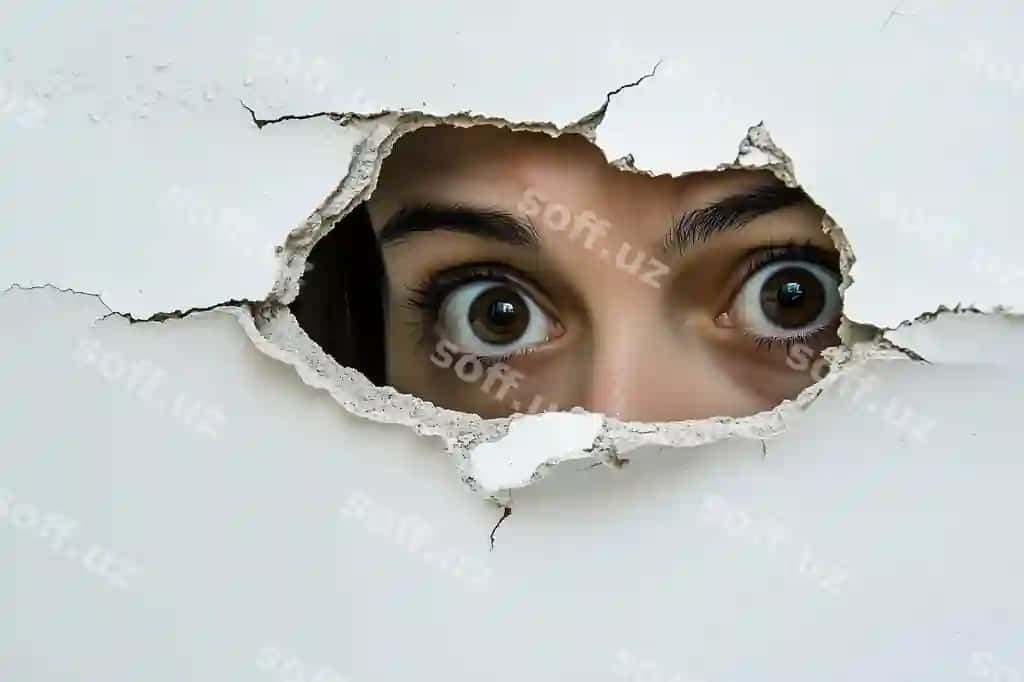 Ayol yuzi oq fonda, ichki devor g'irintisidan qarab chiqmoq, ko'zlari ko'k rangda. | Womans face peering through hole interior wall against white background with blue eyes
