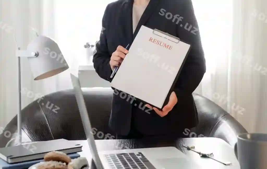 Ayol CV arizasini tutgan qo'llari, uning ish joyi yonida, noutbuk bilan. | Woman hands holding resume application near her workplace with laptop