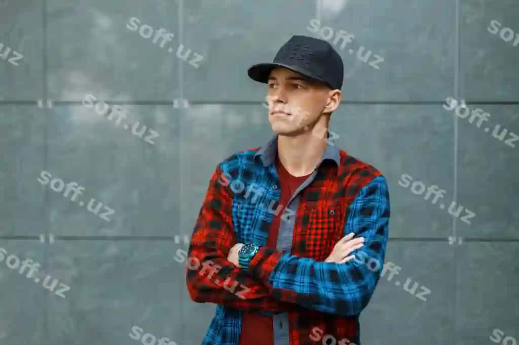 Chiroyli moda akhrora moda futbolka, moda ko'k qizil chiziqli ko'ylak, qora moda basketbol shapkani kulrang eski devor yonida turib. | Handsome stylish young man stylish t shirt trendy blue red plaid shirt black trendy basketball cap stands near gray vintage wall