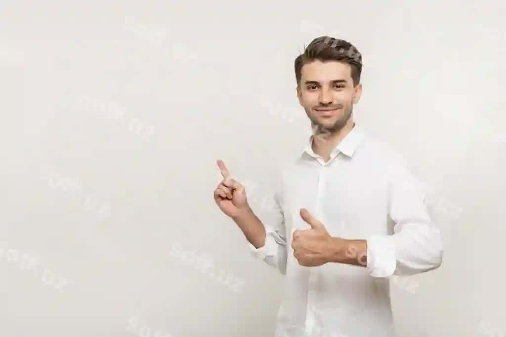 Yosh gulchiq erkak oq ko'ylak kiyin, chap tomonga ko'rsatmoqda, bosh bermoqni ko'rsatmoqda, isolatsiyalangan. | Young smiling man white shirt pointing left with his finger showing thumb up isolated
