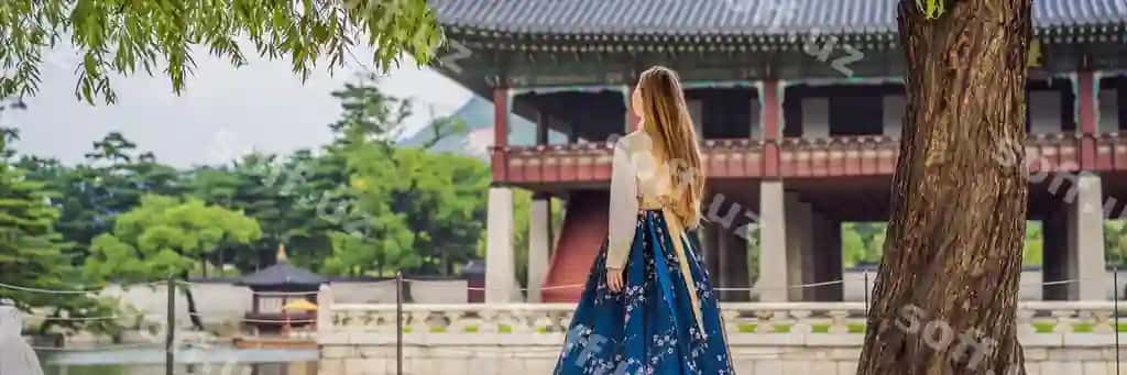 Yosh kavkaz etnikasi ayollari sayohatchilari, hanbok (Koreya milliy kiyimi), Koreyaga sayohat tushunchasi, Koreya milliy kiyimi, koreya milliy kiyimini sinab ko'radigan sayohatchilar, uzun formatdagi banner. | Young caucasian female tourist hanbok national korean dress travel korea concept national korean clothing entertainment tourists trying national korean clothing banner long format