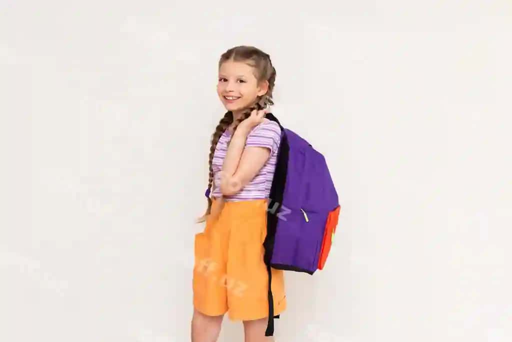 Pigtails shorti kiygan qizcha, orqasi oq rangli fonda maktab xaltasi bilan, bolalar yozgi tayyorgarlik kurslariga o'tadi | Little girl with pigtails shorts with school backpack her back white isolated background preparatory summer courses children