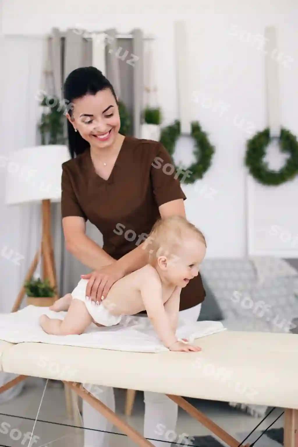 Professional ayollar masseuri zamonaviy, qulay xonada kichik bolalarning massaj kouchida massaj qiladi. | Professional female masseuse makes massage little baby children s massage couch modern cozy room