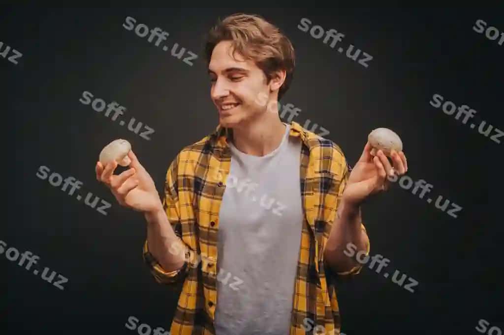 Sariq ko'ylakdagi yosh sarg'ish yigit ikkala qo'lida qo'ziqorinlarni ushlab turibdi | Young blond man yellow shirt is holding mushrooms both hands
