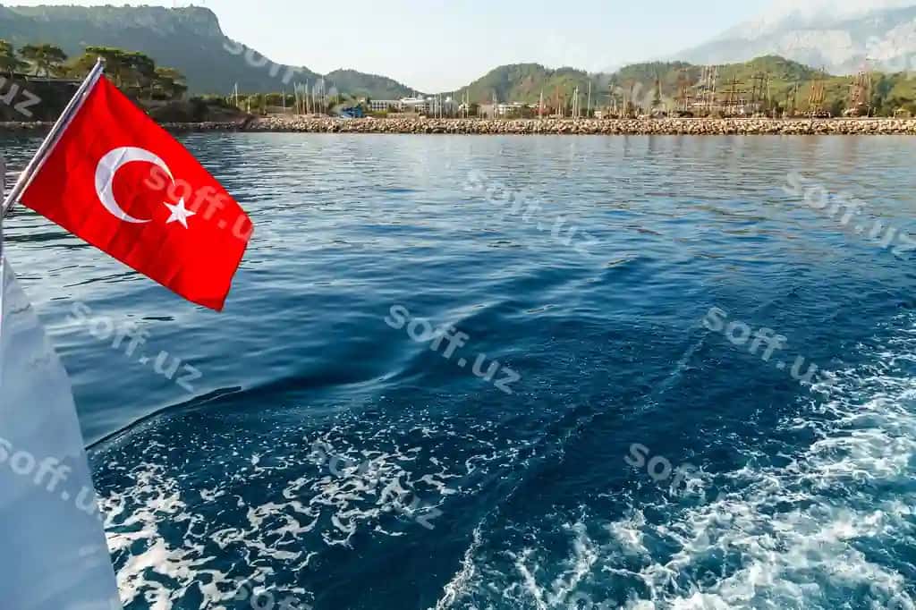 Turk bayrogʻi shamol ostida dengiz sohil orqa fonda | Turkish flag flying wind against background sea coast