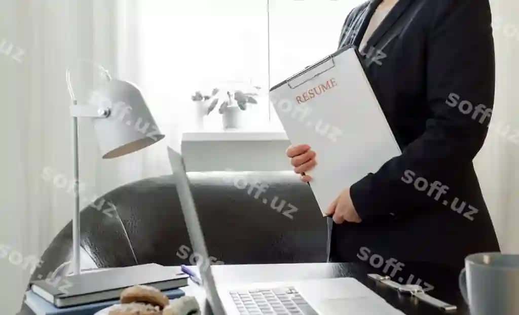 Ayol qo'llarida resume arizasini tutgan, uning ish joyi yonida laptop bilan. | Woman hands holding resume application near her workplace with laptop