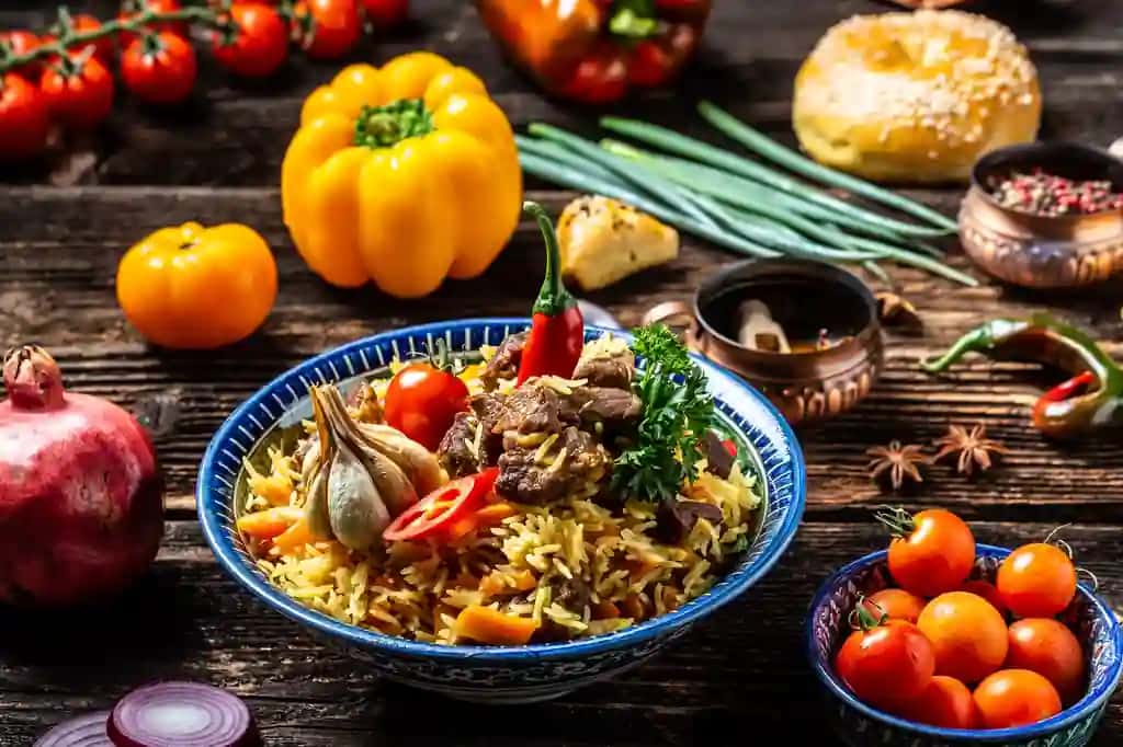 An'anaviy o'zbek taomi palov guruch go'shtli sabzi piyoz likopcha sharqona bezakli o'zbek sharqona taomlari uzun banner formati bo'shliq matni | Traditional uzbek meal called pilaf rice with meat carrot onion plate with oriental ornament uzbek oriental cuisine long banner format space text