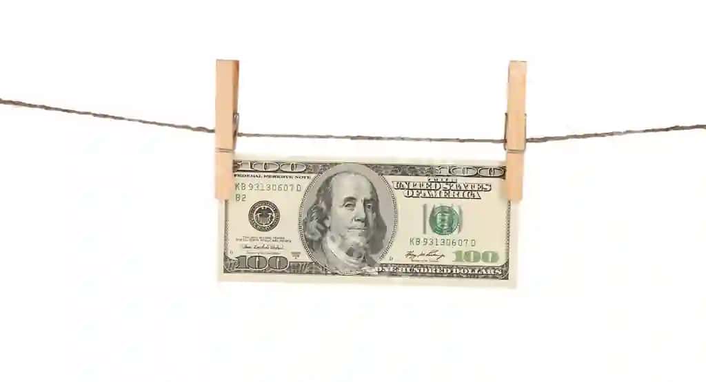 Yuz dollar billlari yogʻochli kirpik bilan ipga ashqan, oq fonda isolatsiya qilingan. | One hundred dollar bills is hanging rope with wooden clothespin isolated white