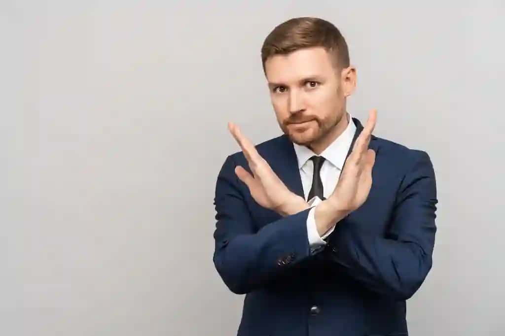 Qiziqarli ishbilarmon kameraning kulrang fonida rad etayotgan qoʻl ishorasini koʻrsatmoqda | Interested businessman showing refuse hands gesture stop sign looking camera grey background