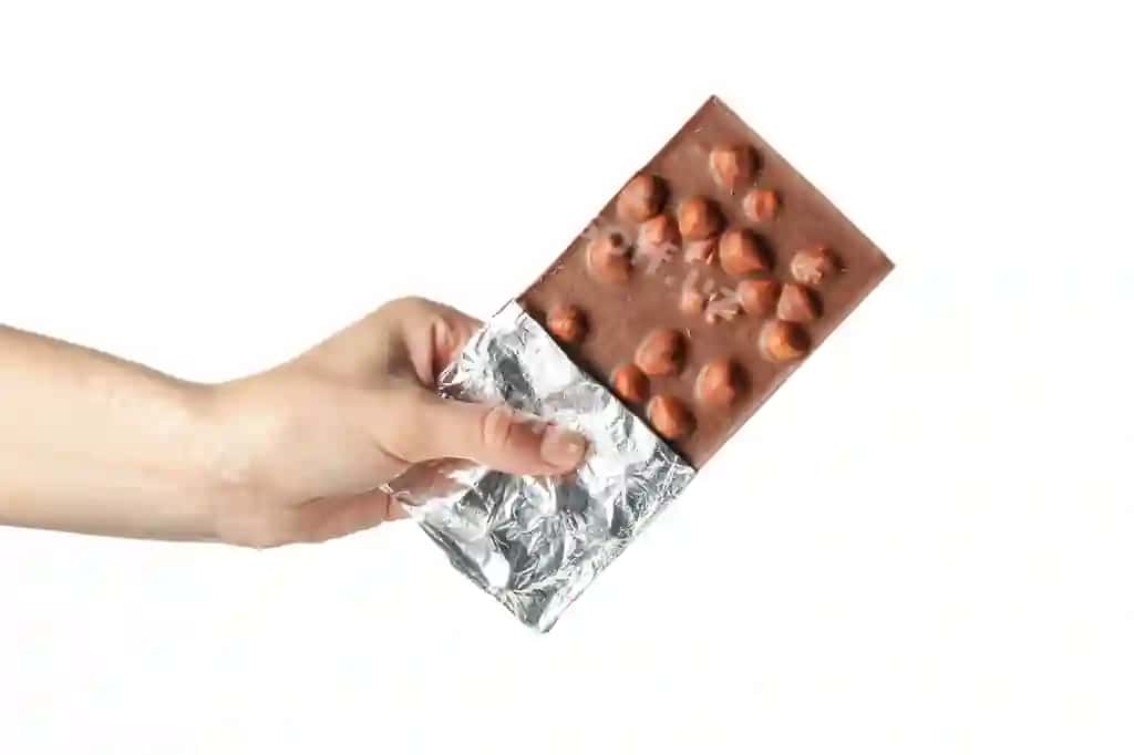 Ayol qo'li oq rangli shokoladli barni ushlab turibdi | Female hand holding chocolate bar isolated white