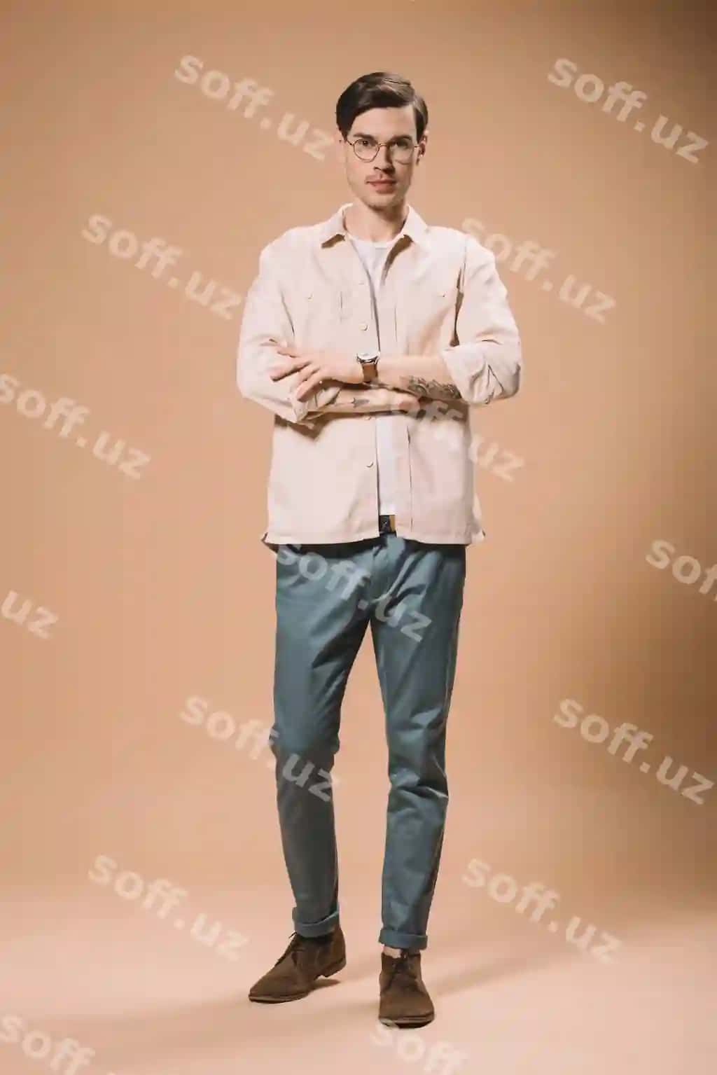 Ishonchli erkak tirmoqda qo'llari sirga olingan bej rangli orqa fon | Confident man standing with crossed arms beige background