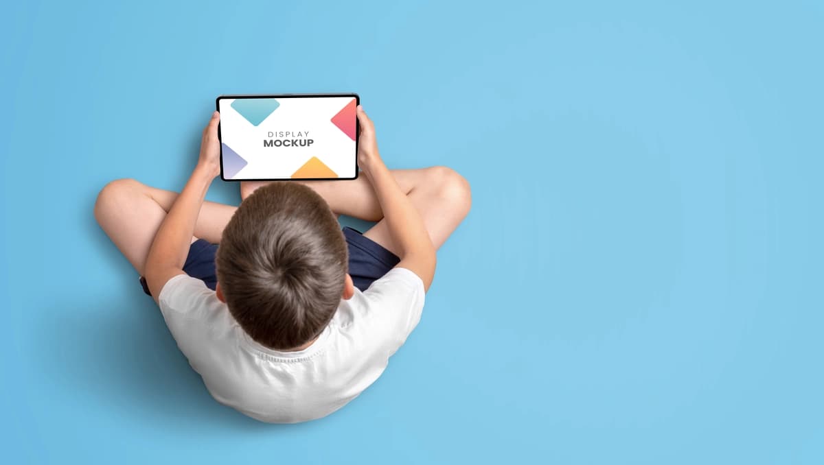 Planshet maketining tepadan ko‘rinishini ushlab turgan bola | Boy holding tablet mockup top view