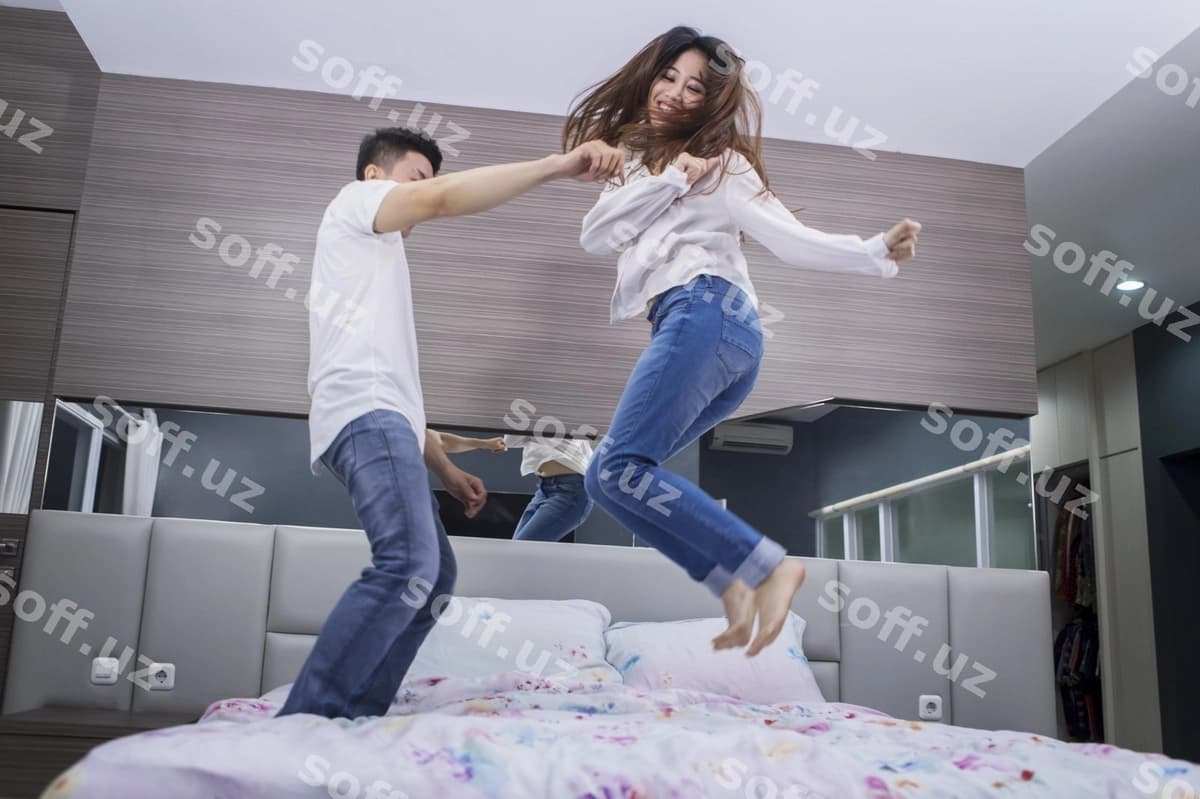 Baxtli juftlik matrax ustida birgalikda sakrab | Cheerful couple jumping together bed