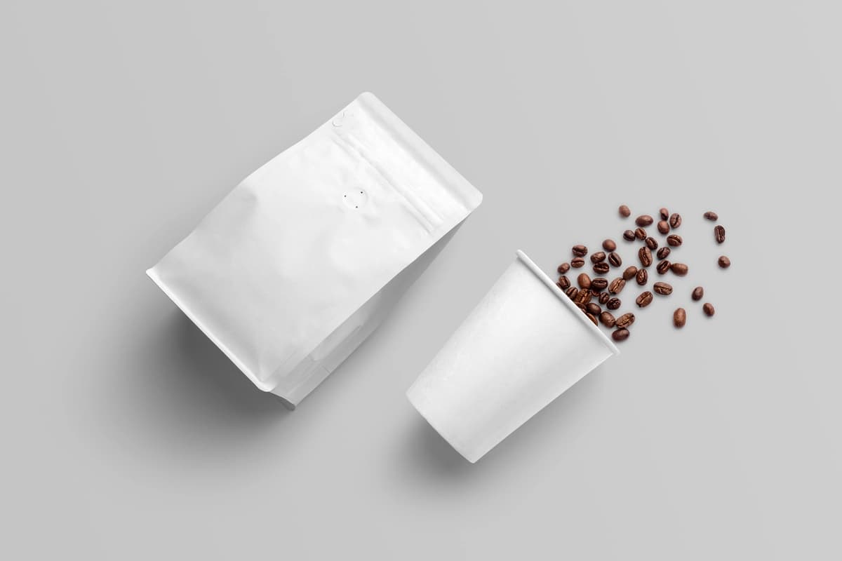 To'kilgan loviya bilan oq qahva qadoqlash maketi | White coffee packaging mockup with spilled beans